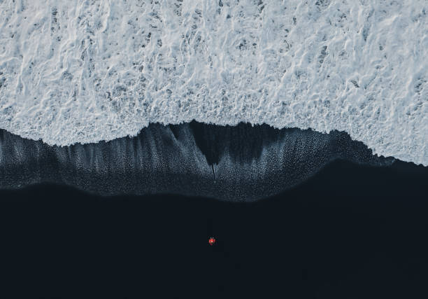 vista aérea de la mujer en la playa de arena negra en islandia - imagen minimalista fotos fotografías e imágenes de stock