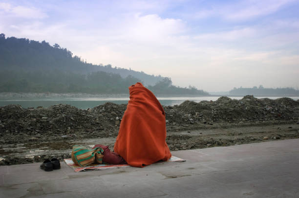 A worshipper meditating alongside the holy Ganges river at sunrise. Rishikesh, India
