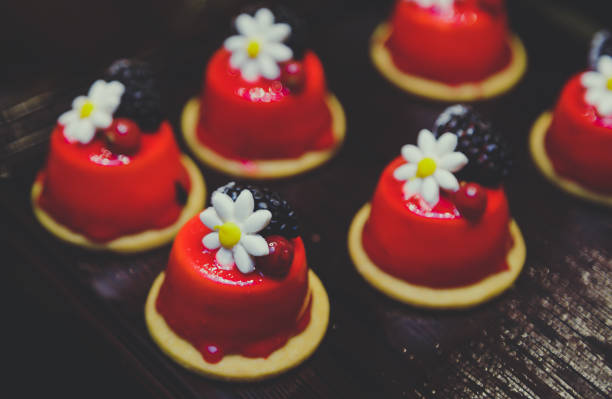 Row of red delicious Christmas cheesecakes with fruit and flower ornated on dishes