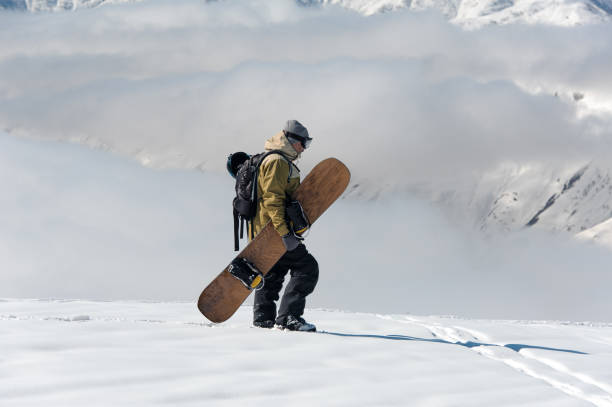 istock Man walking with the snowboard in the mountain resort 1073234474