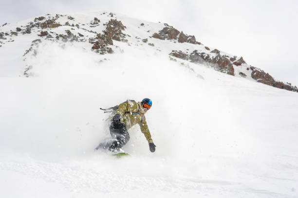 istock Manful snowboarder riding down the slope in the mountain resort 1073234898