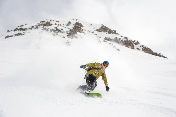 istock Manful snowboarder moving down the hill in the mountain resort 1073234964