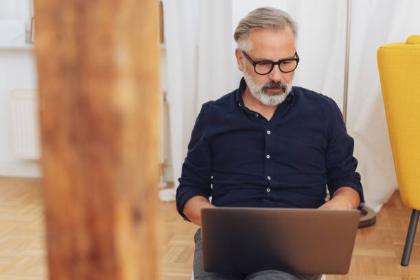 istock Middle-aged man working on laptop at home 1073254552