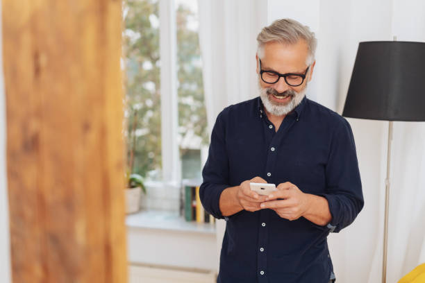 Attractive man smiling as he sends a text message stock photo