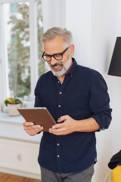 istock Man smiling happily as he reads a tablet-pc 1073257220