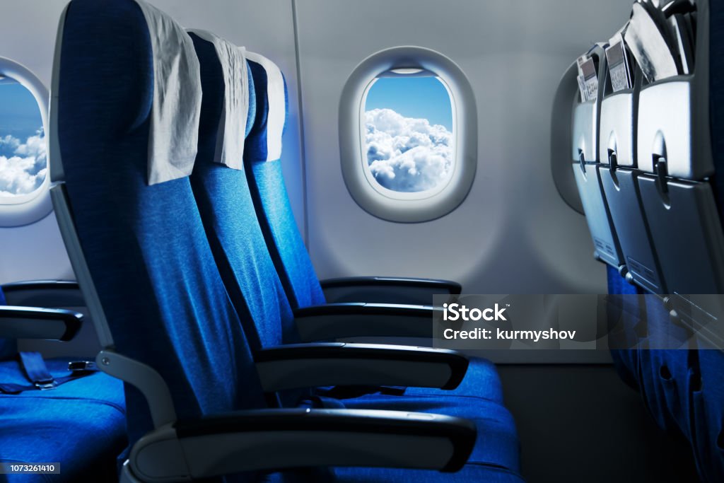 Empty air plane seats. Blue sky and clouds in the window. Airplane interior Airplane Stock Photo