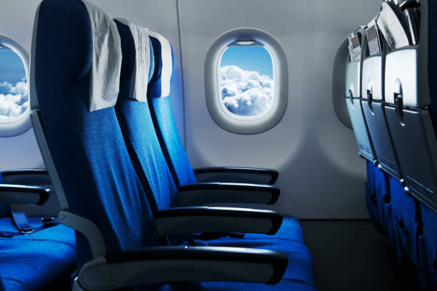 Empty air plane seats. Blue sky and clouds in the window. Airplane interior stock photo