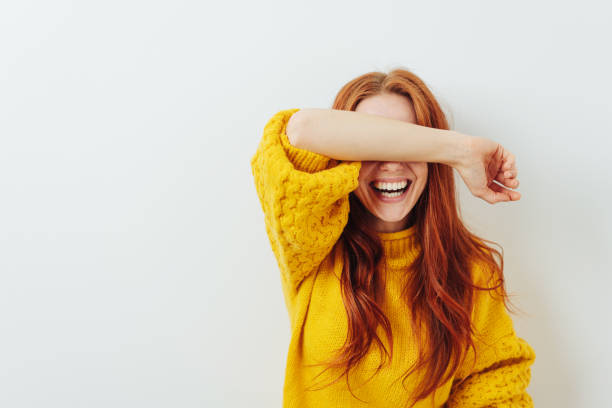 risa a mujer cubriendo sus ojos con su brazo - shy fotografías e imágenes de stock