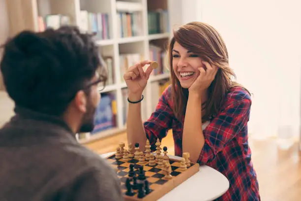 Couple in love sitting on a living room floor, playing chess and having fun