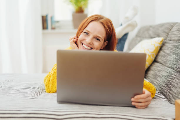 istock Cute friendly young woman relaxing with a laptop 1073272964