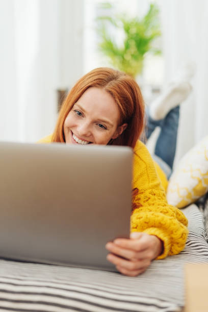 istock Young woman smiling as she reads her laptop screen 1073273274