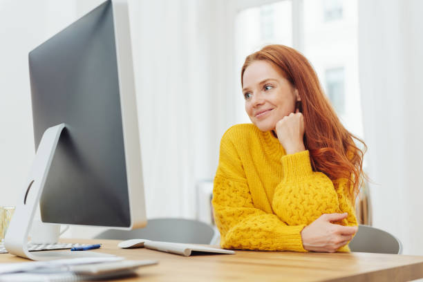 istock Young cheerful woman sitting in front of computer 1073276228