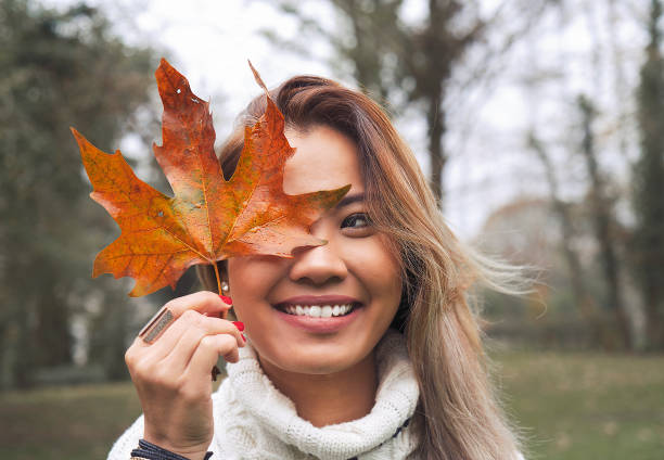 istock Asian woman holding autumn leaf in woods 1073277206