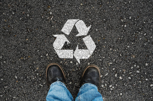 a man with a shoes and recycle sign a man with a shoes is standing next to recycle sign on road asphalt garden hoe photos stock pictures, royalty-free photos & images