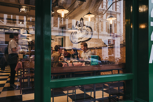 London, UK - November 21, 2018: View through the window of people inside a restaurant in Covent Garden, an area of London popular for cafes and shops.