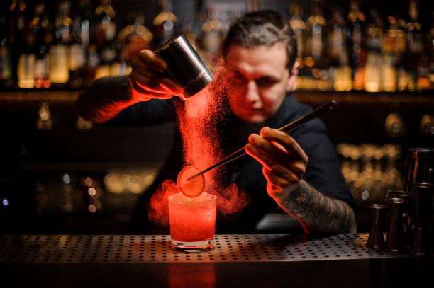 istock Tattooed bartender adding spices powder into a cocktail glass with slice of lemon 1073296352