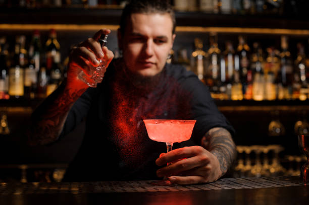 istock Mixologist sprinkling red colored bitter into a cocktail glass 1073296712