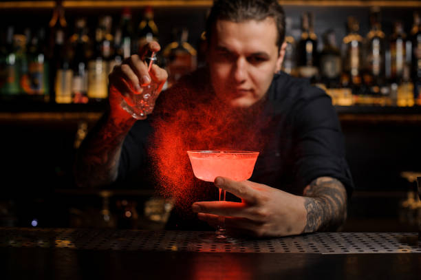 istock Young barman sprinkling red colored bitter into a cocktail glass 1073296790