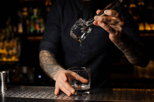istock Tattooed barman putting an ice cube into a cocktail glass 1073297304