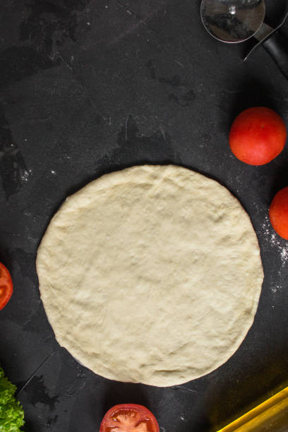 istock pizza - dough, preparation, flat cake (the process of cooking). Top view with copy space 1073301174