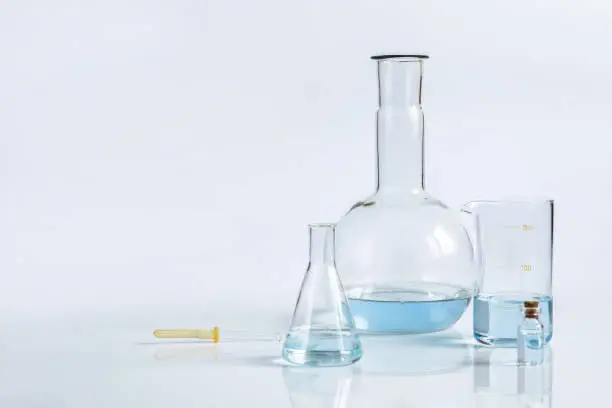 Photo of A set of laboratorian sample flasks of different sizes and shapes are standing on the flat surface.