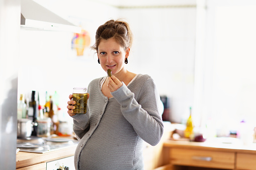 Pregnant Woman Eating Pickled Cucumber In The Kitchen Stock Photo ...