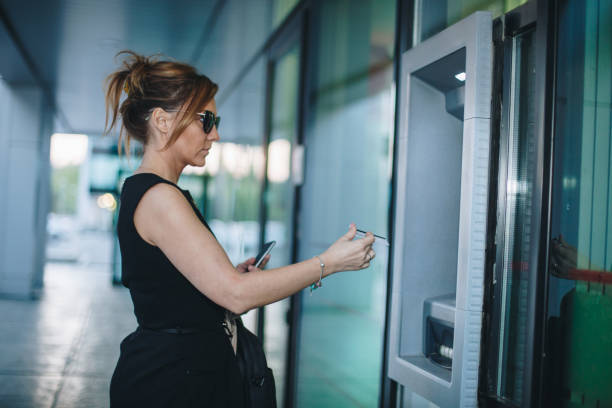 istock Elegant businesswoman using a atm machine with a card 1073345686