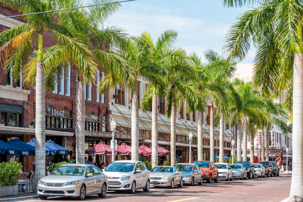 City town street during sunny day in Florida gulf of mexico coast, shopping and restaurants, parked cars, row of green palm trees Fort Myers, USA - April 29, 2018: City town street during sunny day in Florida gulf of mexico coast, shopping and restaurants, parked cars, row of green palm trees fort myers photos stock pictures, royalty-free photos & images
