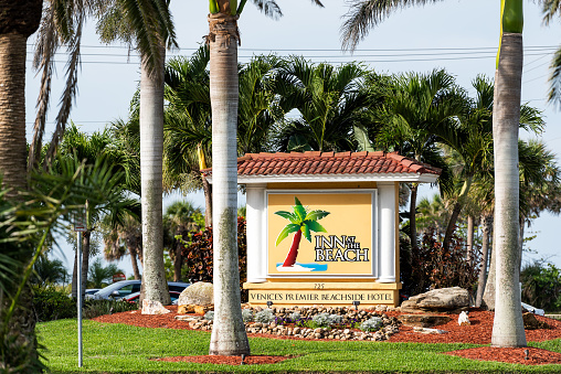 Venice, USA - April 29, 2018: Holiday vacation inn hotel resort in small Florida retirement beach city, town, or village with colorful architecture, in gulf of Mexico, on street sign