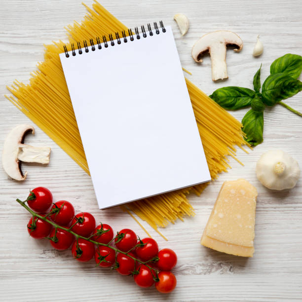 istock Different ingredients for cooking pasta with blank notepad on a white wooden surface, overhead. Top view. Flat lay. From above. Copy space. 1073365994