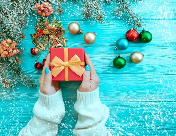 istock women's hands, gift box, Christmas tree branch on a wooden background 1073367124