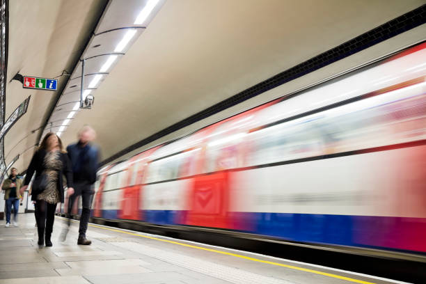 Two subway trains wait at the platform on the newly built London Underground station at Battersea Power Station. The lights of the carriage are reflected on the shiny surface of the platform.
