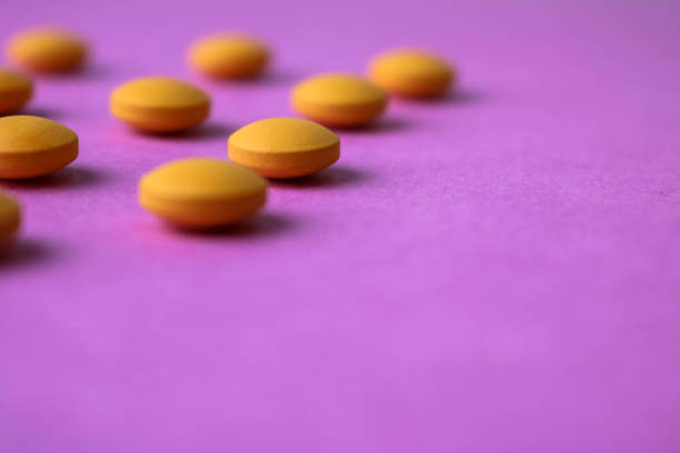 Small yellow orange beautiful medical pharmaceptic round pills, vitamins, drugs, antibiotics on a pink purple background, texture. Concept: medicine, health care. Flat lay, top view Small yellow orange beautiful medical pharmaceptic round pills, vitamins, drugs, antibiotics on a pink purple background, texture. Concept: medicine, health care. Flat lay, top view. statin photos stock pictures, royalty-free photos & images