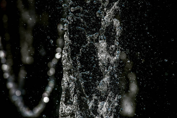 theliquid spruzzi su uno sfondo nero. - fountain water physical pressure splashing foto e immagini stock