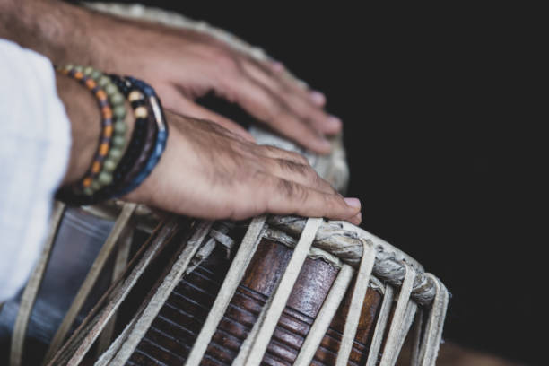 istock Image of a man's hands (wearing beads) playing the Tabla - Indian classical music percussion instrument - black background. 1073385112