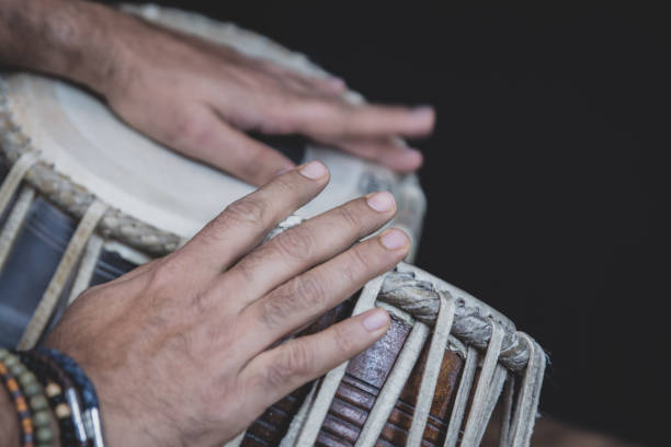 istock Image of a man's hands (wearing beads) playing the Tabla - Indian classical music percussion instrument - black background. 1073385114