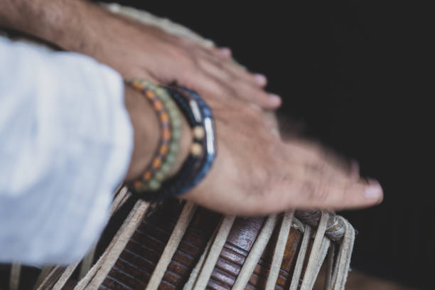 istock Image of a man's hands (wearing beads) playing the Tabla - Indian classical music percussion instrument - black background. 1073385124