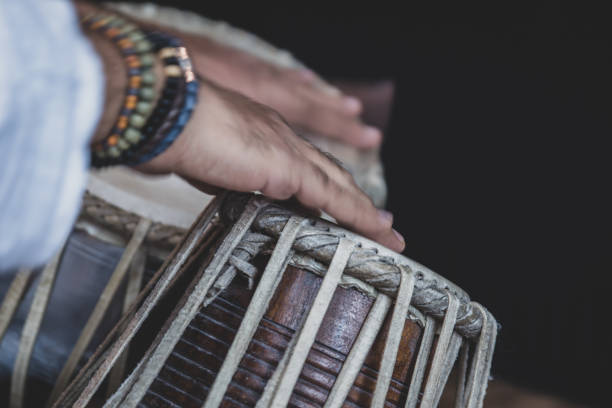 istock Image of a man's hands (wearing beads) playing the Tabla - Indian classical music percussion instrument - black background. 1073385322
