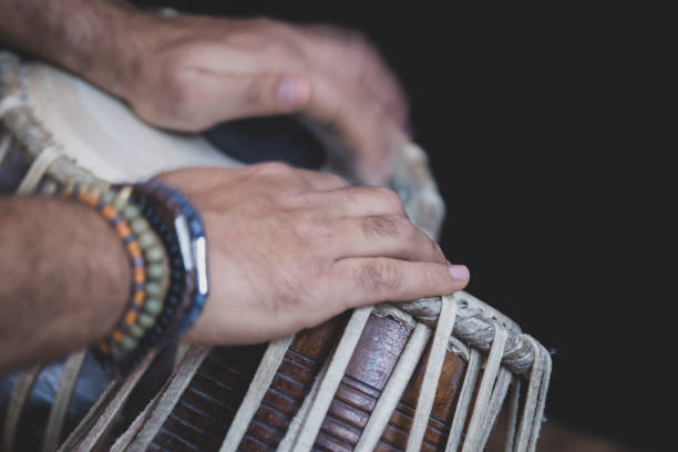istock Image of a man's hands (wearing beads) playing the Tabla - Indian classical music percussion instrument - black background. 1073385328