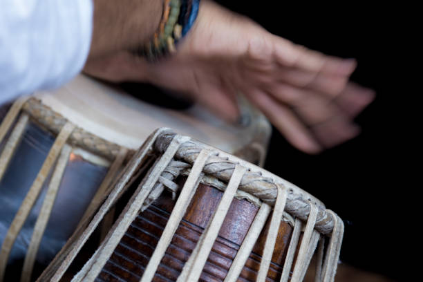 istock Image of a man's hands (wearing beads) playing the Tabla - Indian classical music percussion instrument - black background. 1073385330