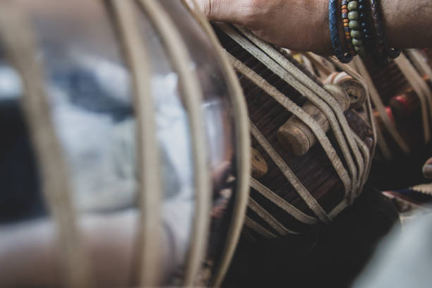 istock Image of a man's hands (wearing beads) playing the Tabla - Indian classical music percussion instrument - black background. 1073385798
