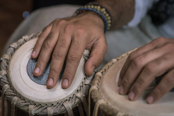 istock Image of a man's hands (wearing beads) playing the Tabla - Indian classical music percussion instrument - black background. 1073386276