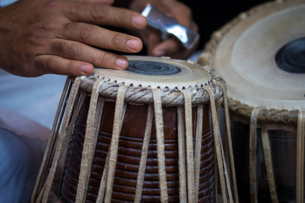 istock Image of a man's hands (wearing beads) playing the Tabla - Indian classical music percussion instrument - black background. 1073387678