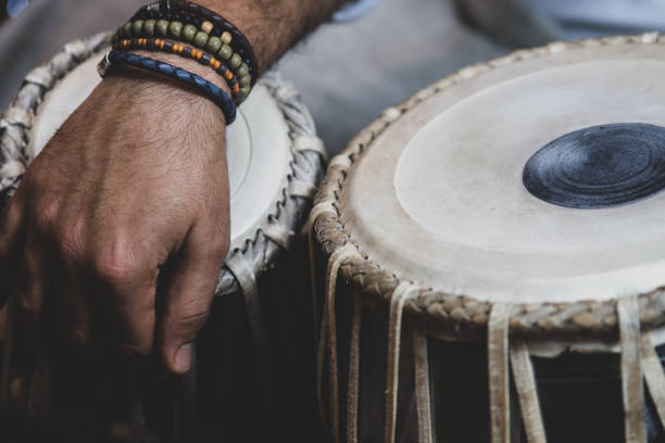 istock Image of a man's hands (wearing beads) playing the Tabla - Indian classical music percussion instrument - black background. 1073387680