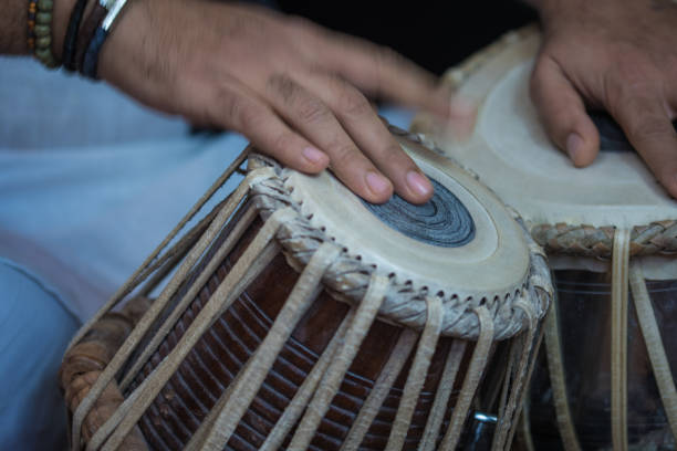 istock Image of a man's hands (wearing beads) playing the Tabla - Indian classical music percussion instrument - black background. 1073388088