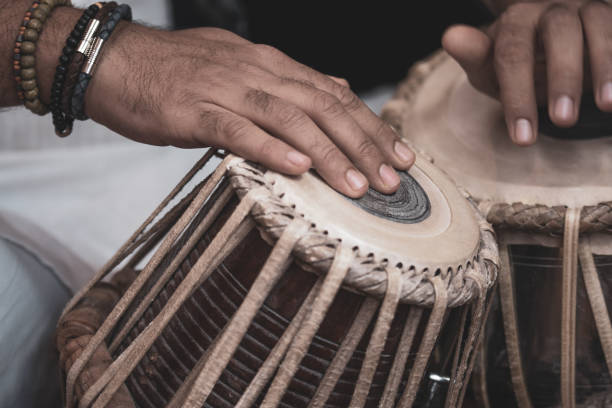 istock Image of a man's hands (wearing beads) playing the Tabla - Indian classical music percussion instrument - black background. 1073388090