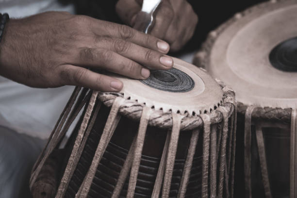 istock Image of a man's hands (wearing beads) playing the Tabla - Indian classical music percussion instrument - black background. 1073388092