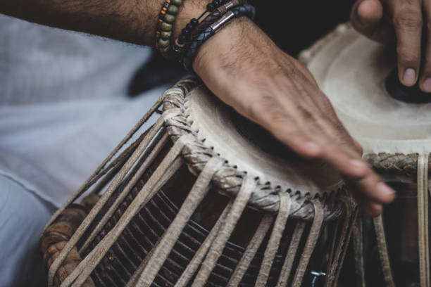 istock Image of a man's hands (wearing beads) playing the Tabla - Indian classical music percussion instrument - black background. 1073388094