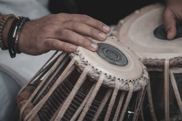 istock Image of a man's hands (wearing beads) playing the Tabla - Indian classical music percussion instrument - black background. 1073388518