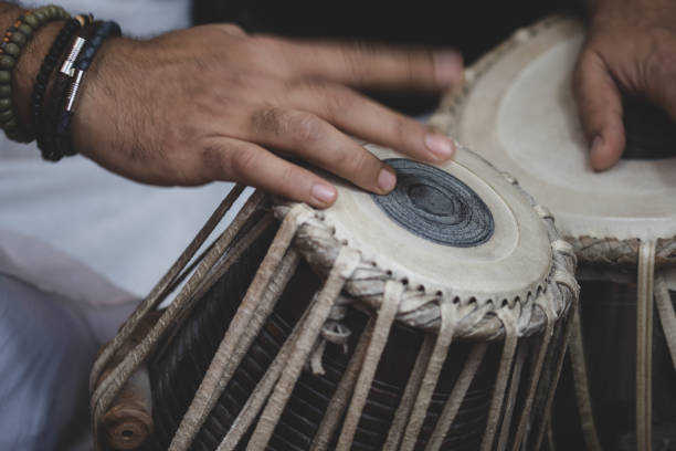 istock Image of a man's hands (wearing beads) playing the Tabla - Indian classical music percussion instrument - black background. 1073388524